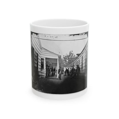 Monochrome 1860s scene of men on a wooden plank walkway between clapboard buildings, one leaning on a crutch.