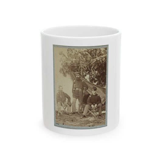 Sepia print showing three uniformed men posed by a canvas tent, one standing with a sword and two seated.