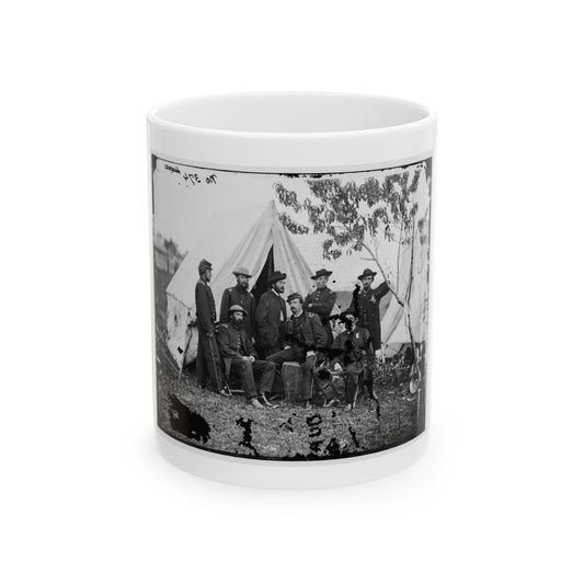 Black and white print of eight Civil War era soldiers posing in front of white canvas tents on grass.