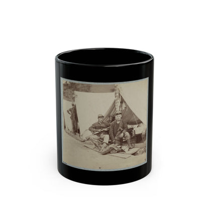 Sepia view of four soldiers in caps resting by a white canvas tent, one holding a rifle in a camp.