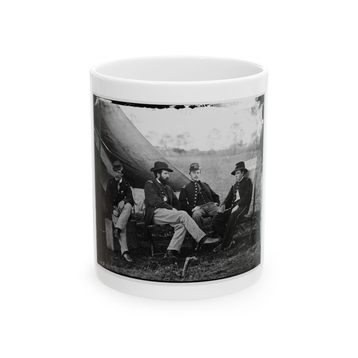 Black and white print of four uniformed officers seated outdoors beside a canvas tent in an open field.