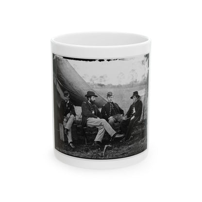 Black and white print of four uniformed officers seated outdoors beside a canvas tent in an open field.