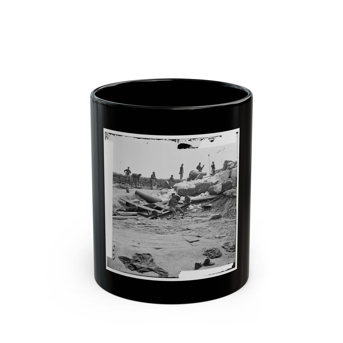 Black-and-white view of soldiers around a dismounted cannon amid sandbags, cannonballs and scattered debris.