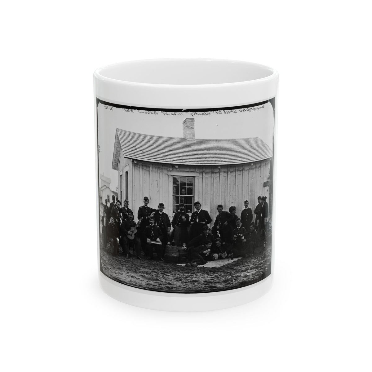 Black-and-white 19th-century print of about twenty uniformed soldiers with a guitar in front of a wooden barracks.