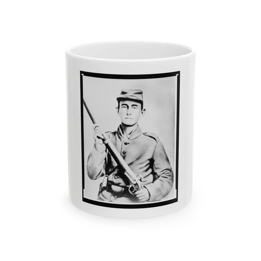 Black and white portrait of a young soldier in a kepi cap holding a rifle across his chest against a pale backdrop.