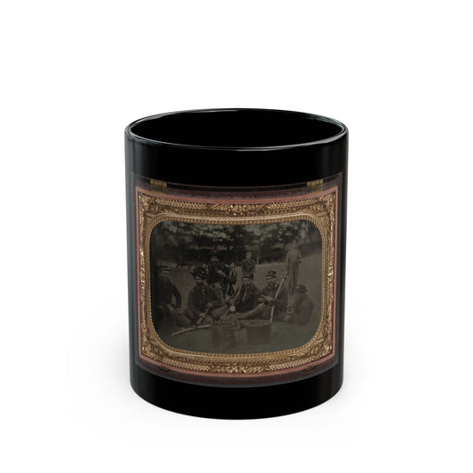 Sepia tintype of seven soldiers resting on grass in camp, some holding sabres and tin cups, in a gilt case.