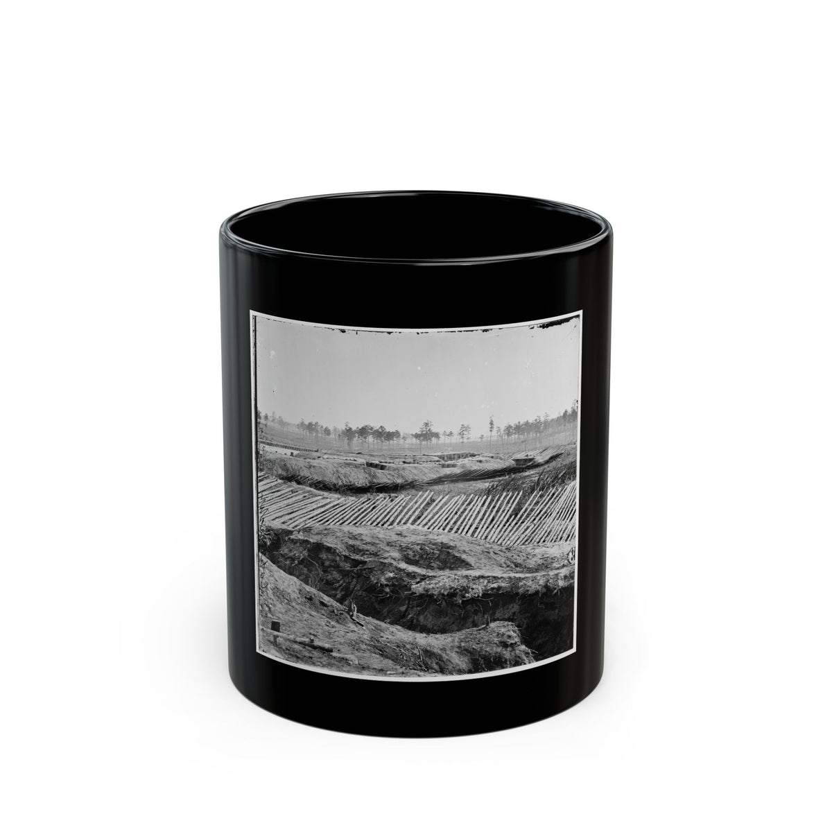 Black and white view of earthworks with rows of sharpened timber stakes angled across embankments under a pale sky.