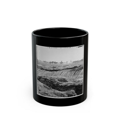 Black and white view of earthworks with rows of sharpened timber stakes angled across embankments under a pale sky.