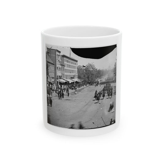 Black and white 1860s view of mounted riders and marching troops on a city avenue lined with spectators.