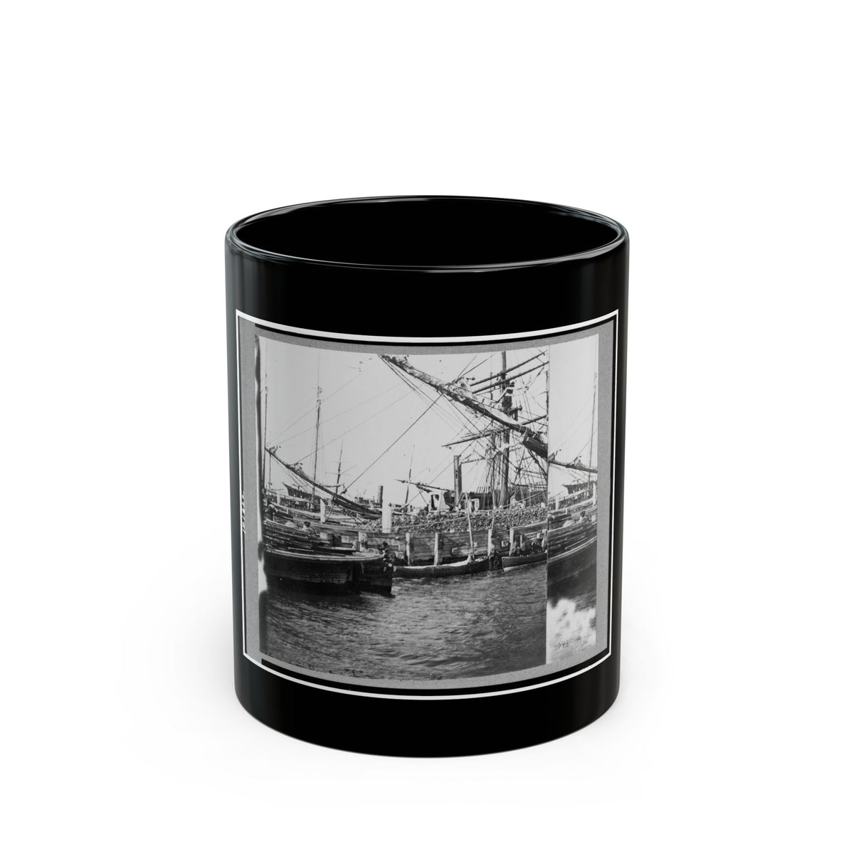 Black and white 19th-century view of sailing ships with rigging and small boats at a wooden wharf.