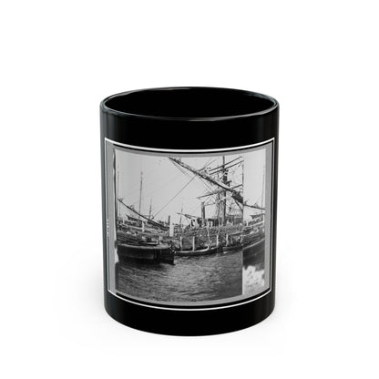 Black and white 19th-century view of sailing ships with rigging and small boats at a wooden wharf.