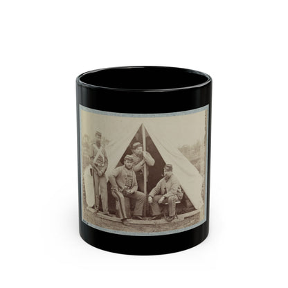 Sepia print of four soldiers in forage caps grouped before a white canvas tent on a wooden platform.