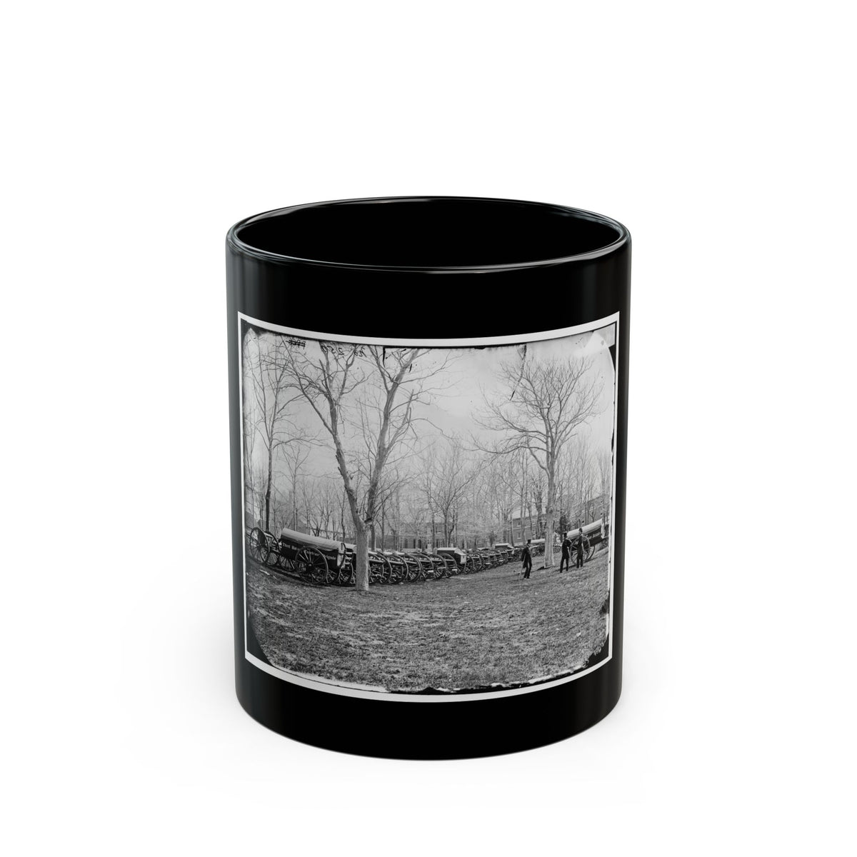 Black and white historical view of covered army wagons lined up on a field beneath bare trees, with two men nearby.