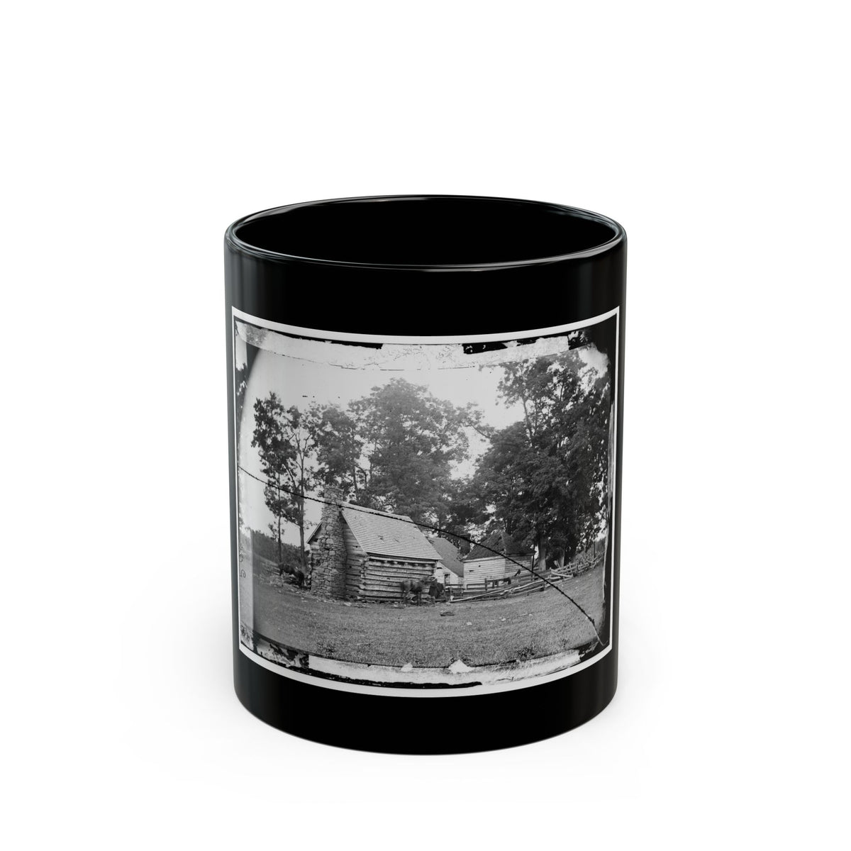 Black and white view of a log cabin with a stone chimney, grazing horses and split-rail fencing.
