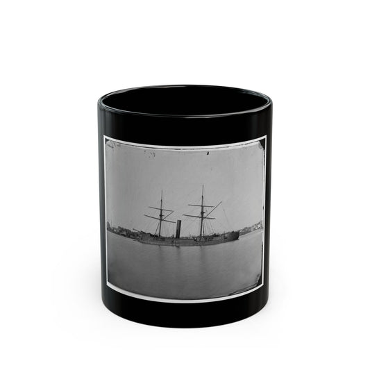 Black and white 1860s view of a two-masted steam warship with one smokestack on a calm river beside a town.