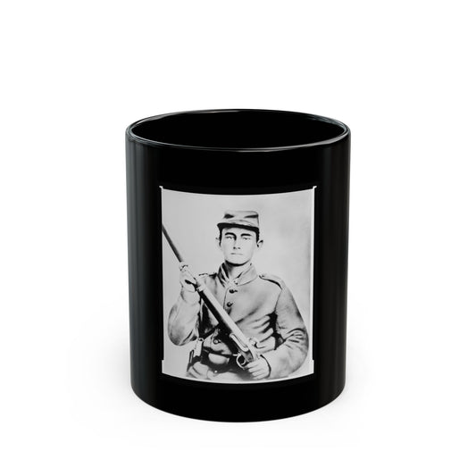Black and white portrait of a young soldier in a kepi cap holding a rifle across his chest against a pale backdrop.