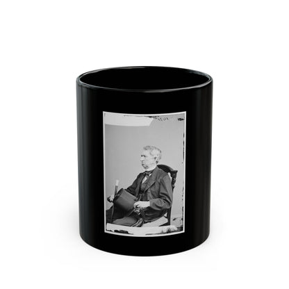 Black and white portrait of an elderly man in a dark suit, seated in a carved chair and holding a top hat.