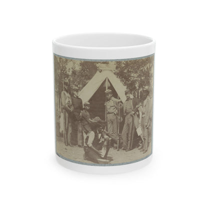Sepia print showing several soldiers with rifles beside a peaked canvas tent, with one figure kneeling in front.