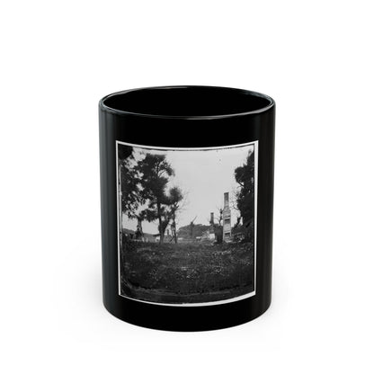 Black and white scene of brick chimneys standing among ruins and trees above a field of wildflowers.