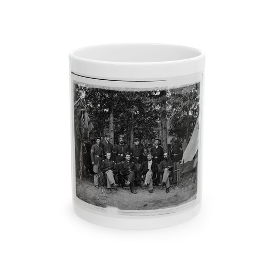 Black and white print of ten uniformed soldiers posed in a wooded camp beside a canvas tent.