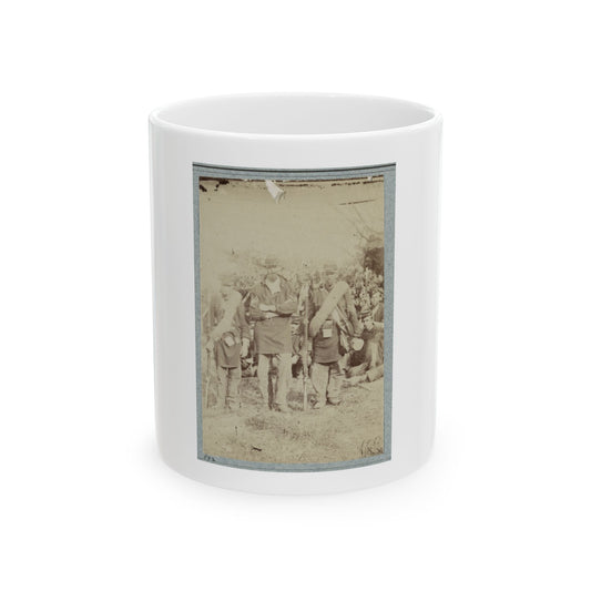 Sepia print showing soldiers in kepis with bedrolls and canteens, standing and sitting in an open field.