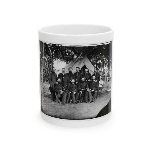 Black and white group portrait of ten uniformed officers in front of a canvas tent beneath trees on grass.