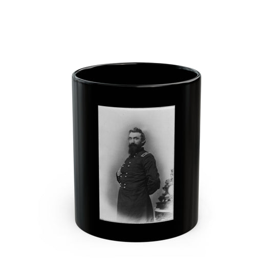 Black and white studio portrait of a bearded man in a double-breasted military frock coat beside an ornate pedestal.