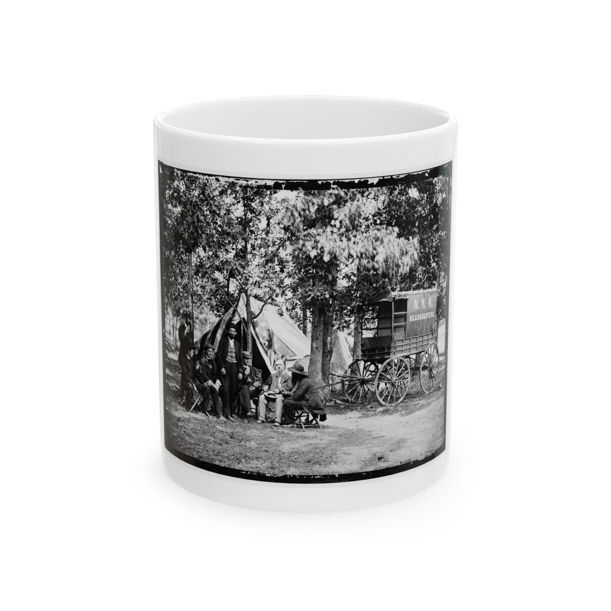 Black-and-white historical view of seven men seated by a canvas tent and a headquarters wagon.