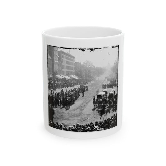 Black and white 19th-century view of crowds lining an avenue as a military parade passes toward a domed building.