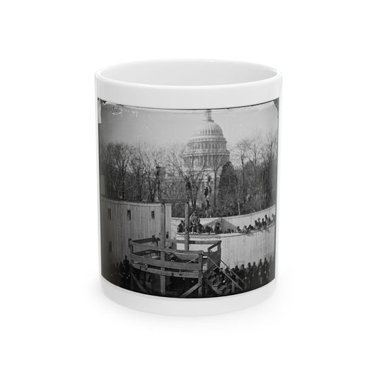 Black and white 19th-century view of a wooden scaffold and crowd on a fence, with a domed capitol behind bare trees.