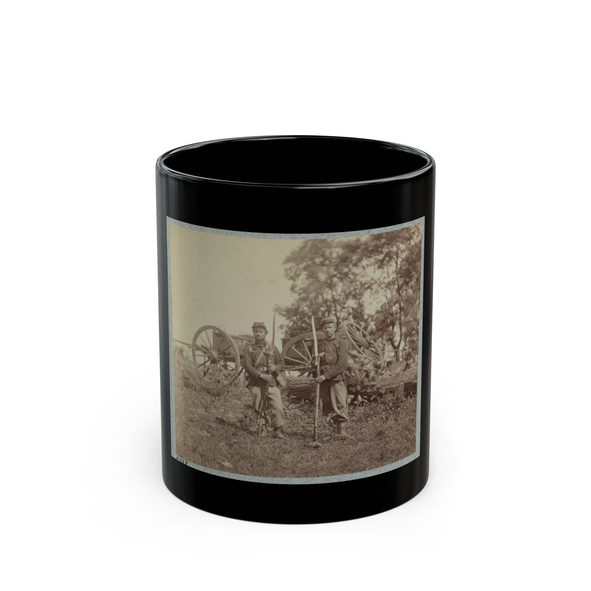 Sepia-toned print of two soldiers with bayoneted rifles standing in a field before wagon wheels and a fallen log.