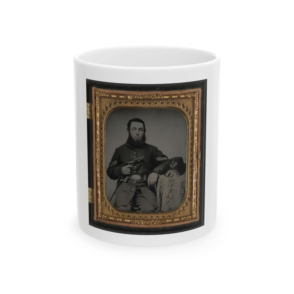 Sepia portrait of a bearded soldier holding a revolver beside a kepi on a draped table, in an ornate gilt case.