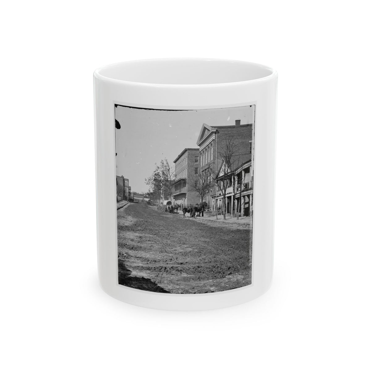 Black and white 1860s view of a muddy unpaved street lined with brick buildings, with horses and a wagon.