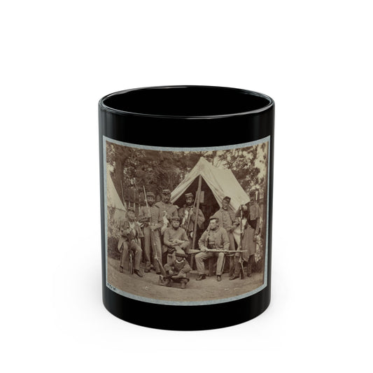 Sepia print of about nine soldiers with rifles posed before a large canvas tent, with a small figure in front.