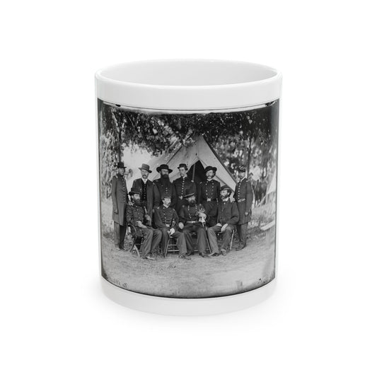 Black and white vintage group portrait of about ten uniformed officers posed before a canvas tent under trees.