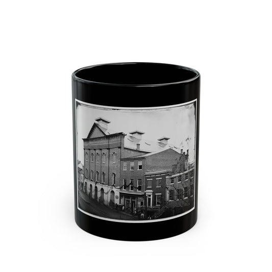 Black and white 1860s view of a brick building with arched openings and bunting swags above a street.