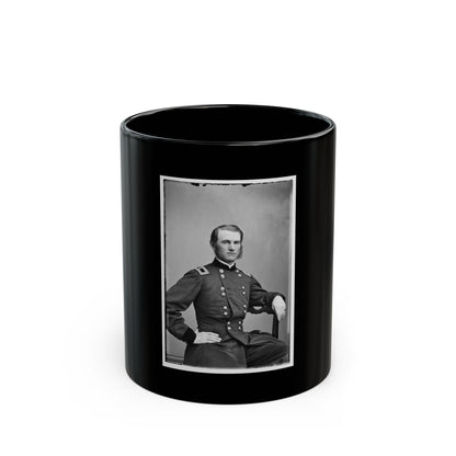 Black and white portrait of a seated man in a dark double-breasted officer's coat with one hand on his hip.