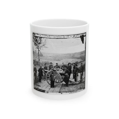 Black and white 1860s view of nine uniformed officers gathered around a spoked cannon on a wooden platform.