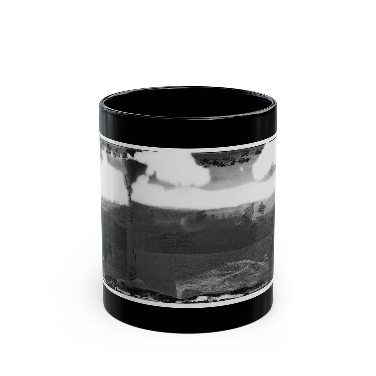 Black and white stereograph of a seated man with binoculars looking over rolling fields and scattered trees.