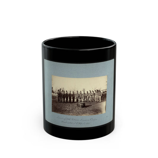 Sepia 1865 view of a uniformed band in plumed caps and striped jackets standing in a row before a bass drum.