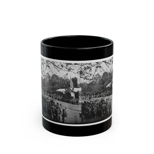 Black and white mid-19th-century view of a crowd of soldiers before a flag-decorated reviewing stand under trees.