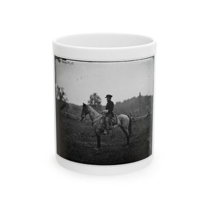 Black-and-white 1860s view of a mounted officer on a grey horse in an open field, a man standing at left.
