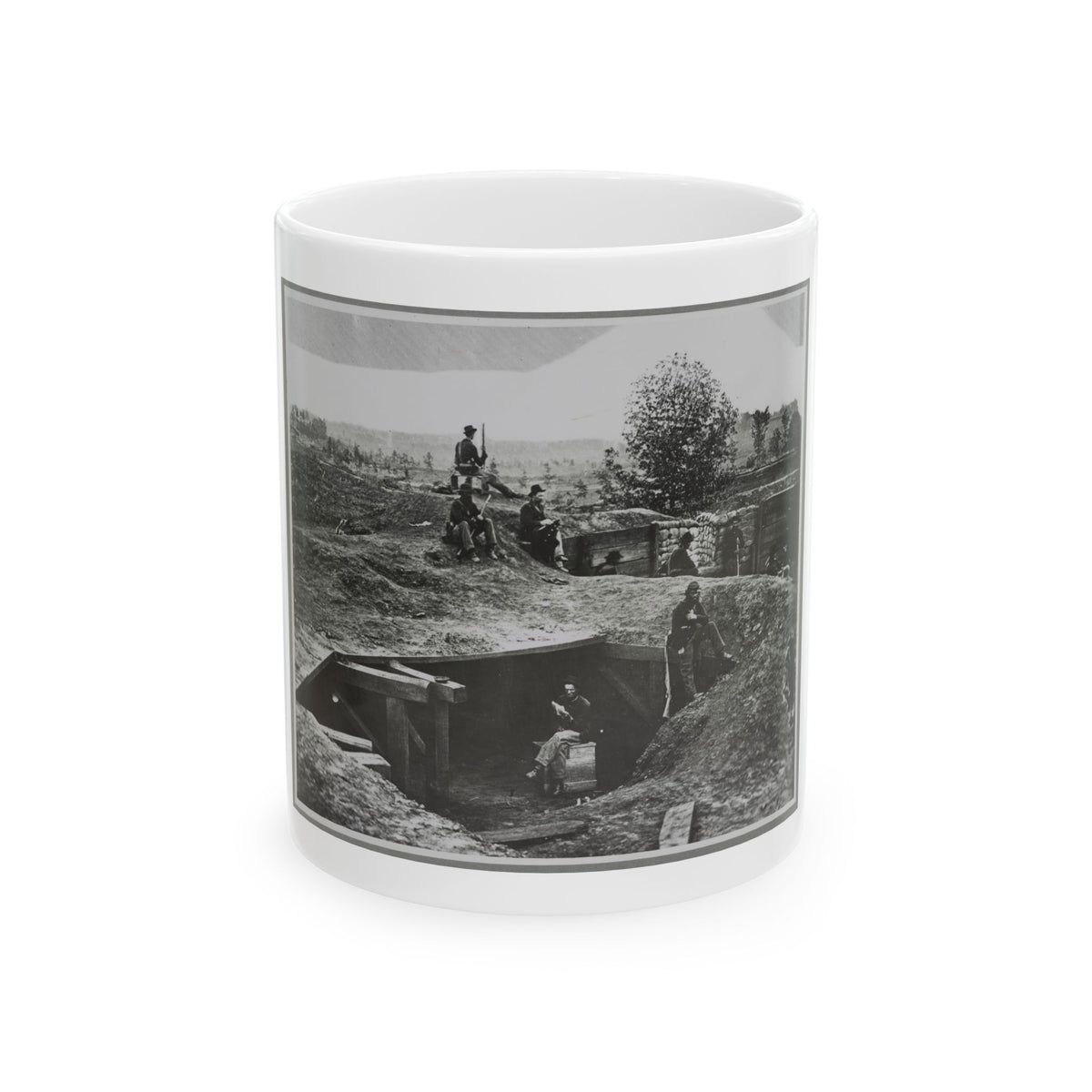 Black and white view of soldiers resting in an earthwork trench beside a timber dugout and sandbag walls.