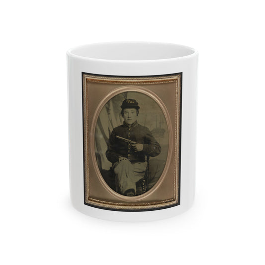 Sepia tintype portrait of a young seated soldier in a dark uniform and kepi, holding a revolver, inside an oval frame.