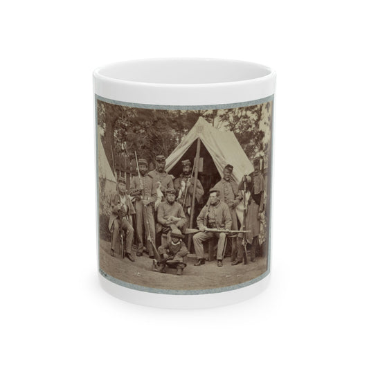 Sepia print of about nine soldiers with rifles posed before a large canvas tent, with a small figure in front.