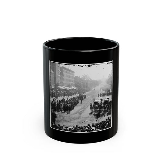 Black and white 19th-century view of crowds lining an avenue as a military parade passes toward a domed building.