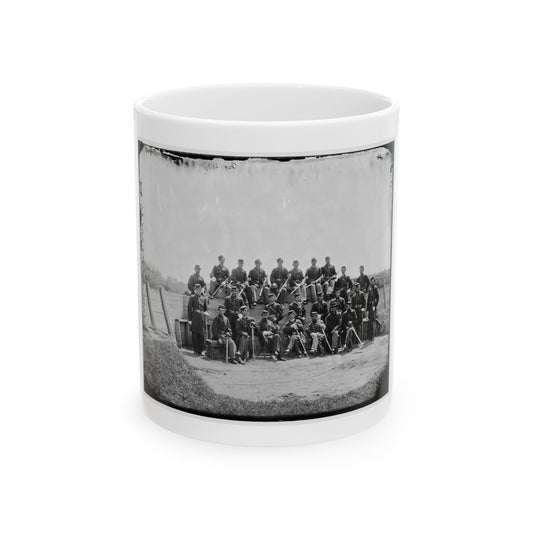 Black and white group portrait of about two dozen uniformed soldiers posed with swords on an earthwork.