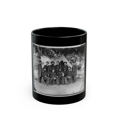 Black and white vintage group portrait of about ten uniformed officers posed before a canvas tent under trees.