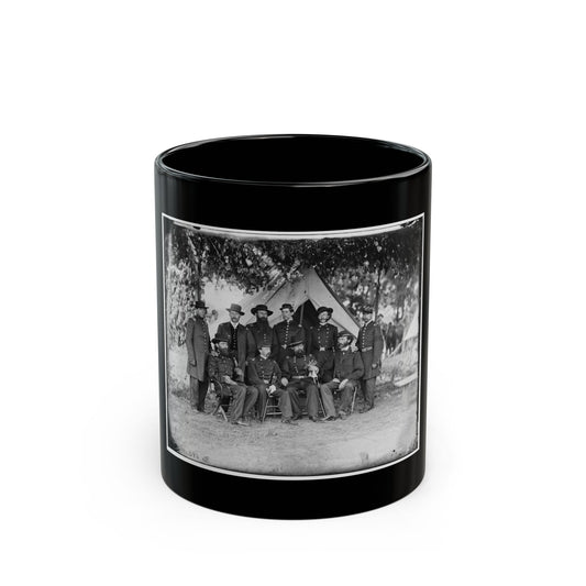 Black and white vintage group portrait of about ten uniformed officers posed before a canvas tent under trees.