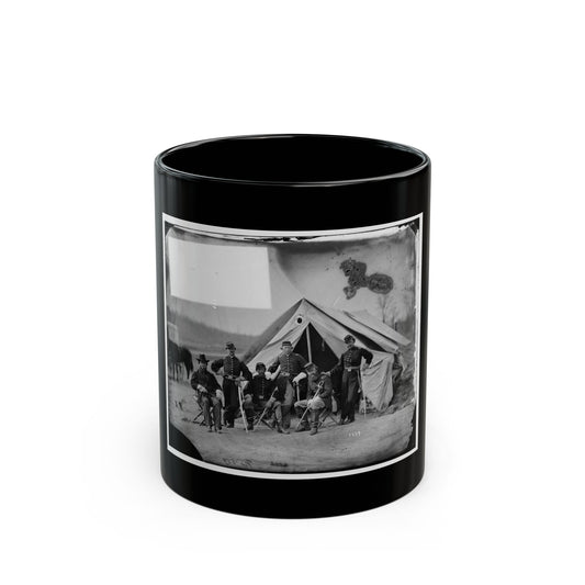 Black and white view of six 1860s officers posed before a canvas tent, some seated on folding chairs.